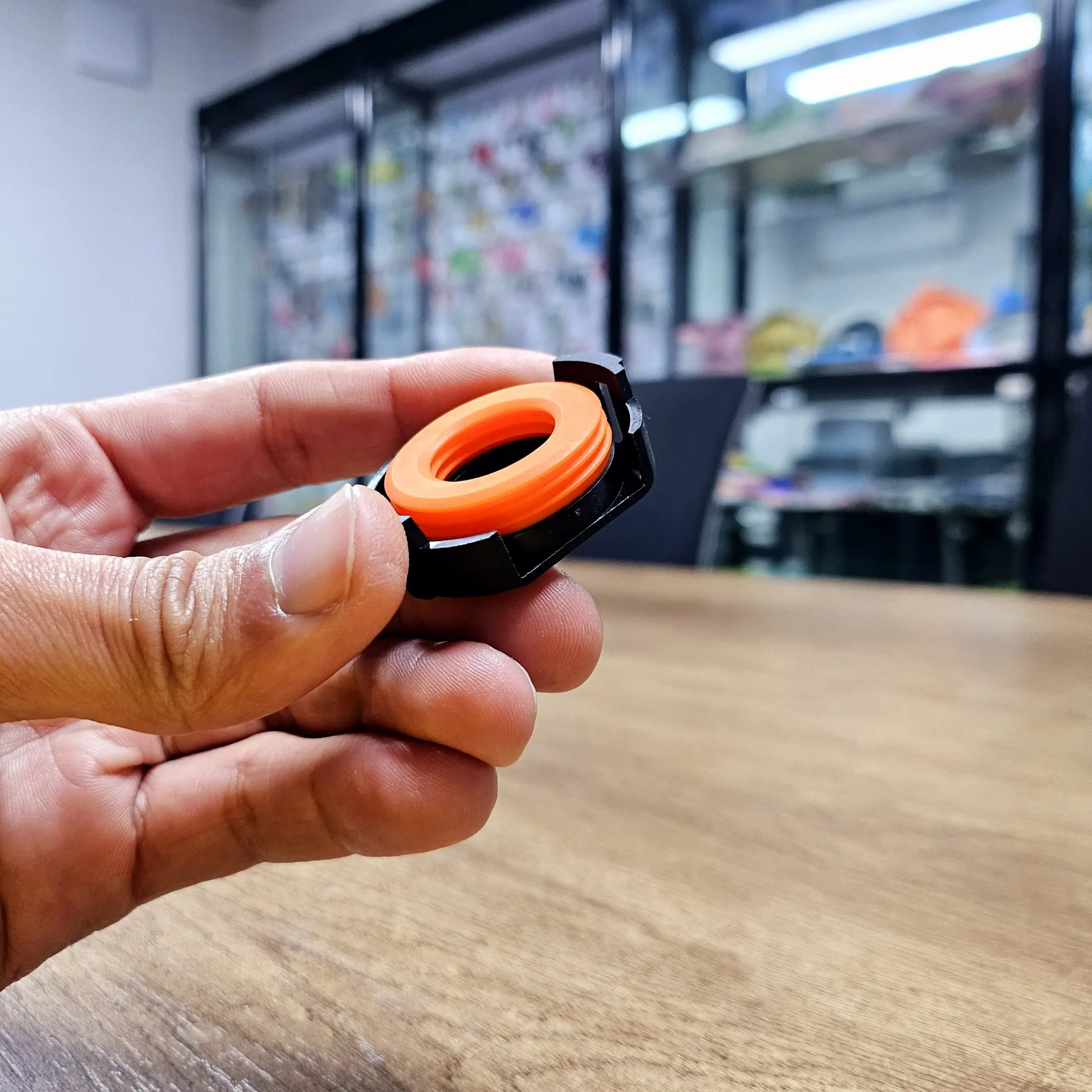 Orange silicone sealing ring overmolded onto black plastic threaded nut